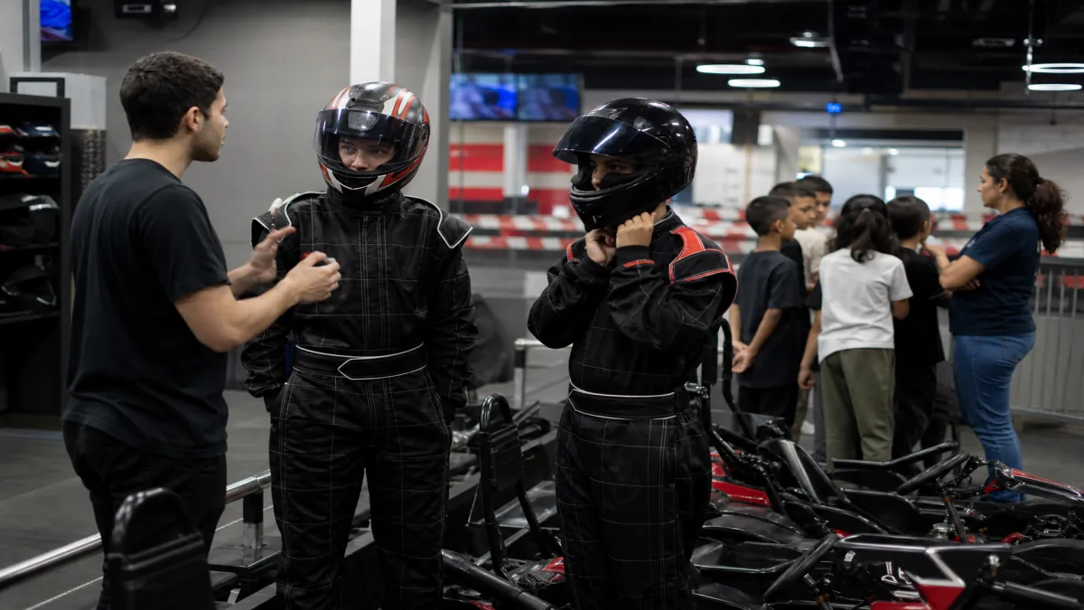 Alunos em kart recebem briefing de monitores em pista indoor premium antes da corrida de kart para grupos escolares.